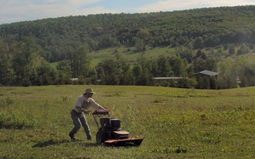 image of a man operating a walk behind field mower - photo taken by Cadie on May 28, 2006
