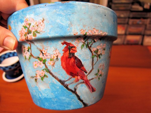 Clay pot painted with a cardinal and apple blossoms.