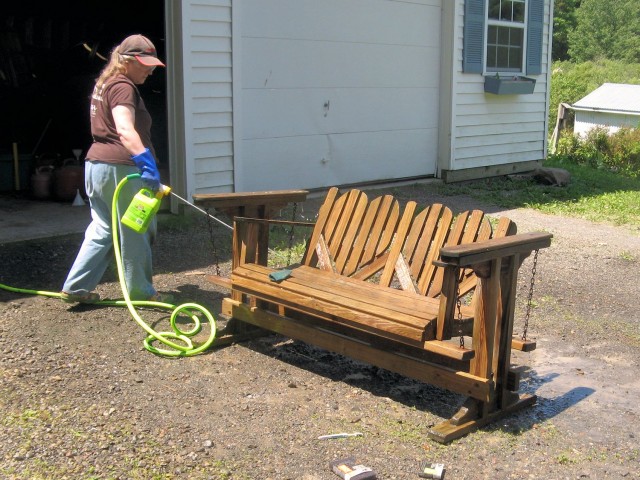 Spraying deck cleaner to restore wooden outdoor furniture
